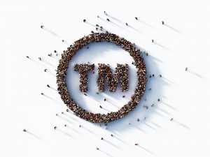 overhead view of a crowd of people, shaped into the TM trademark symbol, protect your intellectual property