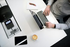 Overhead view of a business professional working on a laptop, researching registered trademarks.